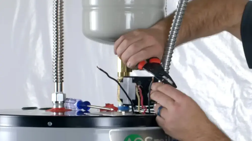 Hands working on the wiring at the top of a tank water heater