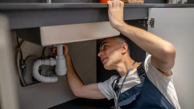 Plumber reaching under a sink to install a garbage disposal