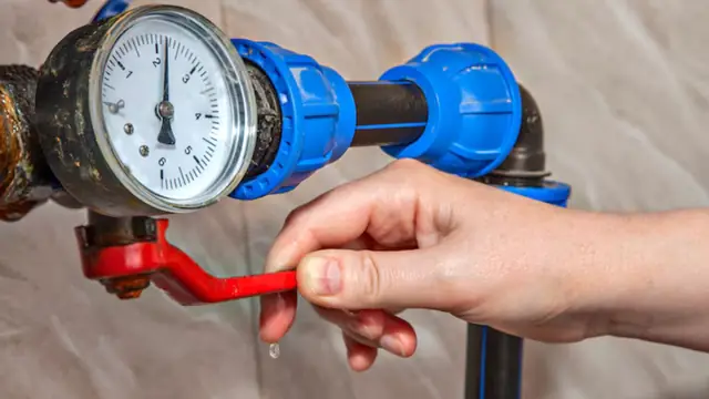 Hand turning a valve beside a pressure gauge